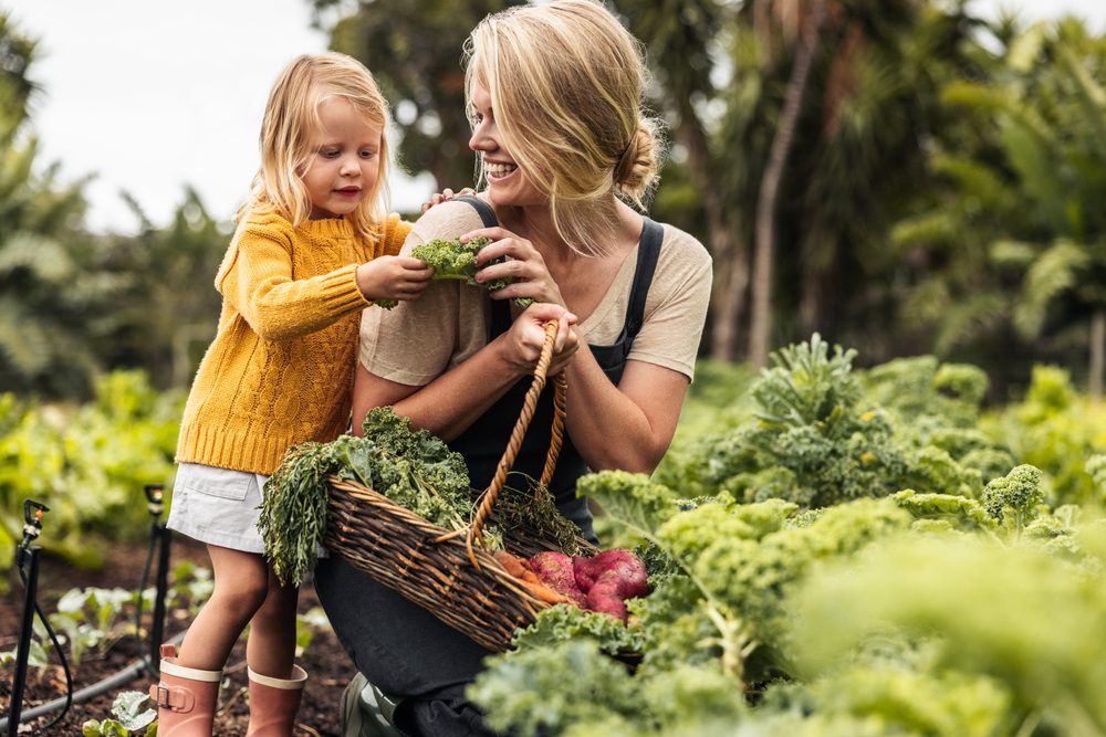 woman and young girl in a garden with a basket of vegetables