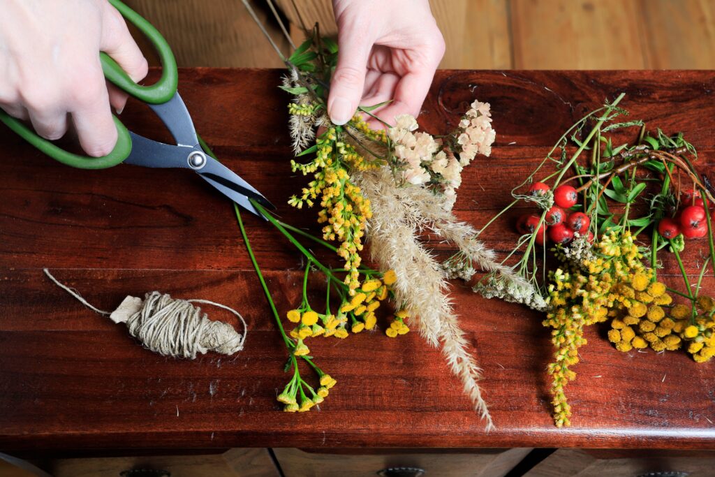 hands holding scissors and herbs to make an arrangement